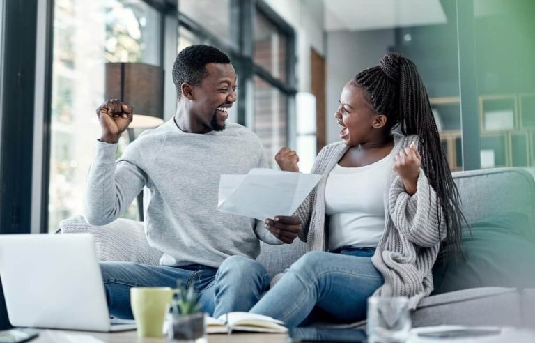 nothing-feels-better-than-being-debt-free-shot-young-couple-celebrating-while-going-through-paperwork-home-min